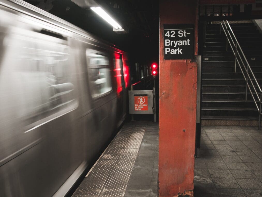 New York City Subway System at 42 St Bryant Park, with a train speeding by on the left side