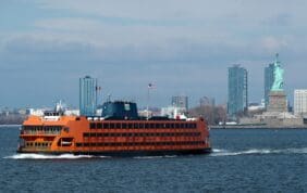 A Staten Island Ferry in front of the Statue of Liberty, with a beautiful view for those on NYC sightseeing tours