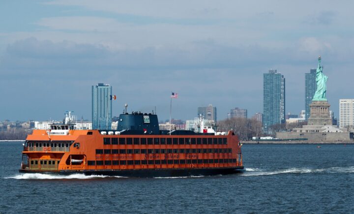 A Staten Island Ferry in front of the Statue of Liberty, with a beautiful view for those on NYC sightseeing tours