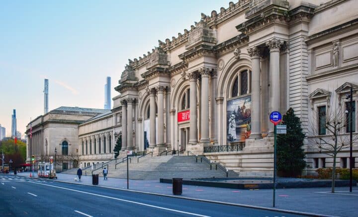 Metropolitan Museum of Art building seen from the street, with the beautiful architecture, bustling streets, & pedestrians