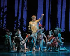 An adult male performer and several young children are staging a New York City Ballet show at Lincoln Center