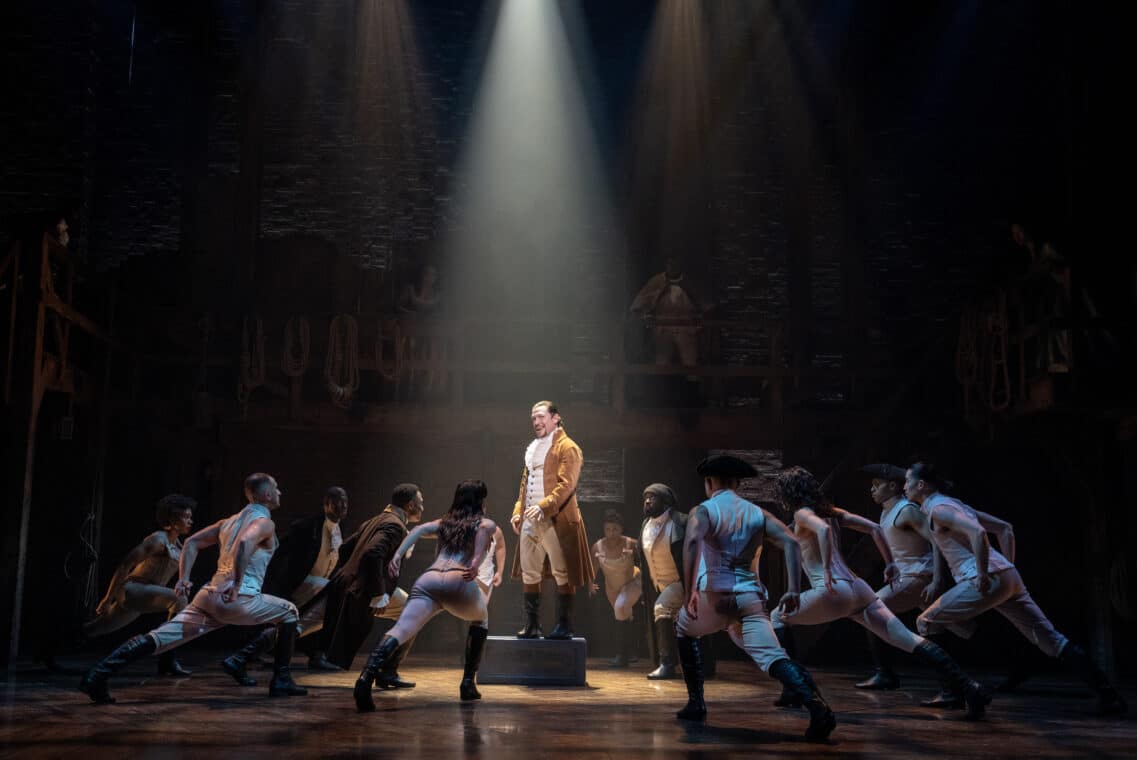 A man stands surrounded by several people in the show of 'Hamilton' at the Richard Rodgers Theatre