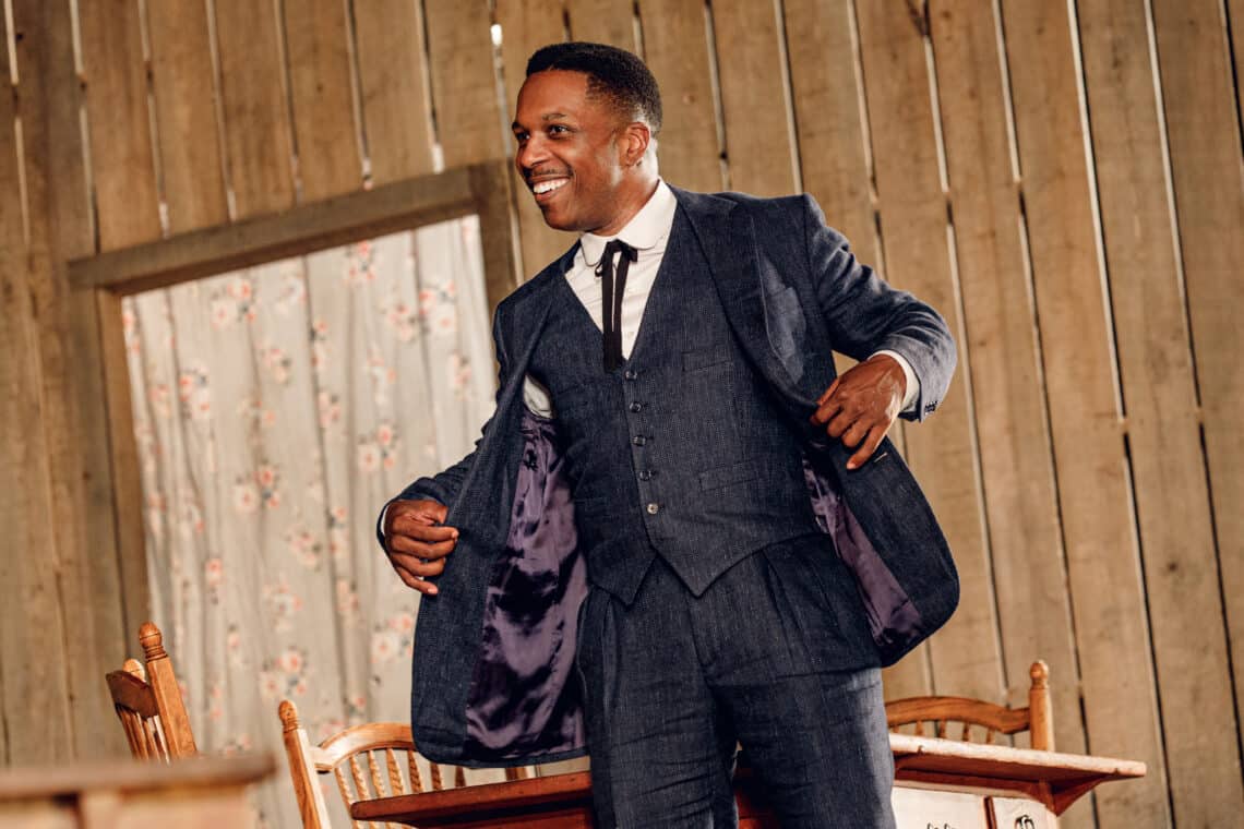 A Black man in a suit performs in the Broadway musical 'Purlie Victorious' inside a wooden house