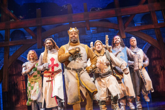 A group of men in costumes are dancing together in the Broadway musical Spamalot