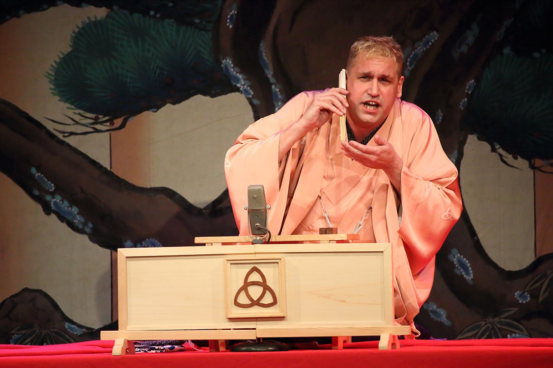 A man using a white box is performing at the Katsura Sunshine's Rakugo even