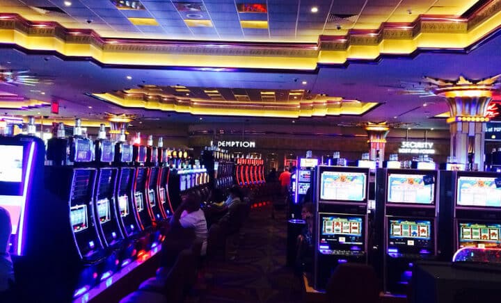 The vibrant glow of the neon signs in Empire City Casino, NYC, highlighting the rows of slot machines and gaming tables