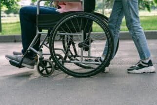 Person in Blue Denim Jeans Sitting on Black Wheelchair