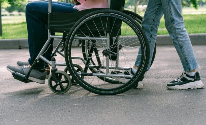 Person in Blue Denim Jeans Sitting on Black Wheelchair