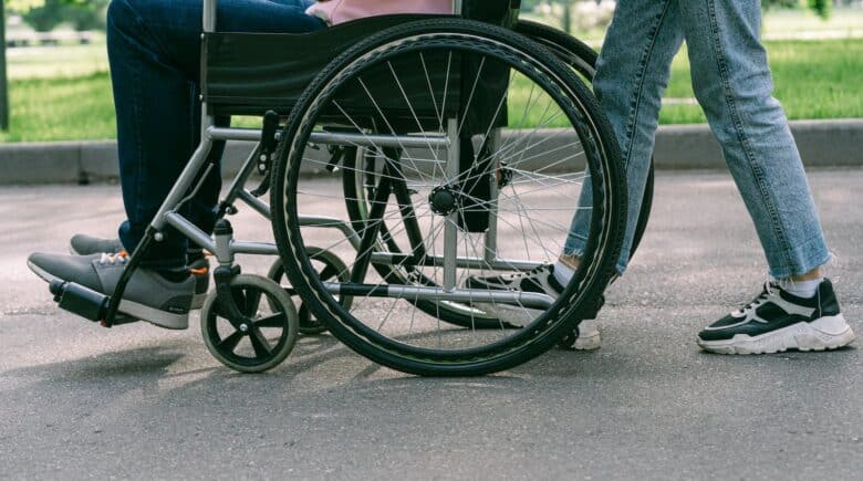 Person in Blue Denim Jeans Sitting on Black Wheelchair