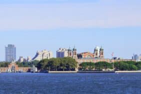 Ellis Island in New York Harbor, featuring the historic immigration station with the Manhattan skyline in the background