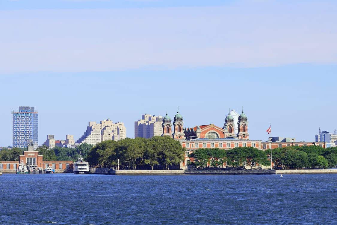 Ellis Island in New York Harbor, featuring the historic immigration station with the Manhattan skyline in the background