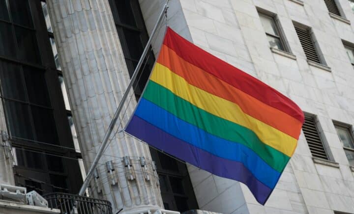 a rainbow flag flying in front of a tall building