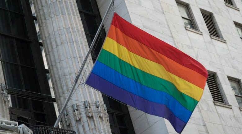 a rainbow flag flying in front of a tall building