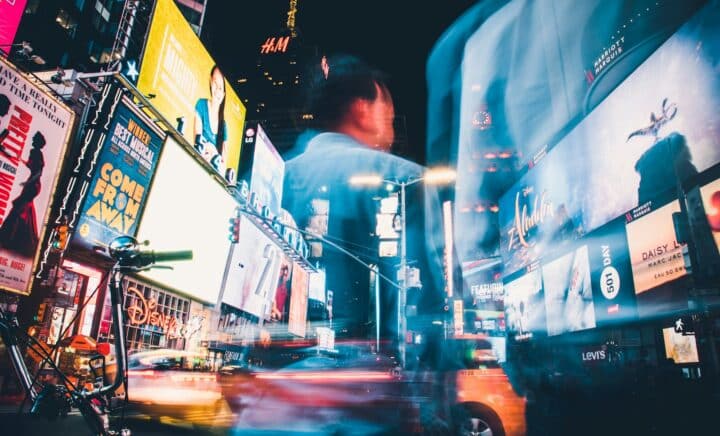 man in blue shirt standing near cars during night time