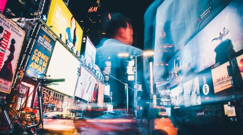 man in blue shirt standing near cars during night time