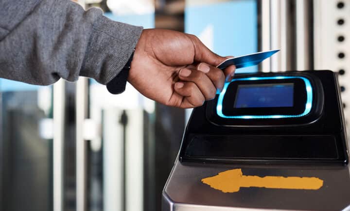 hand tapping an OMNY card on a contactless payment terminal in a New York City subway