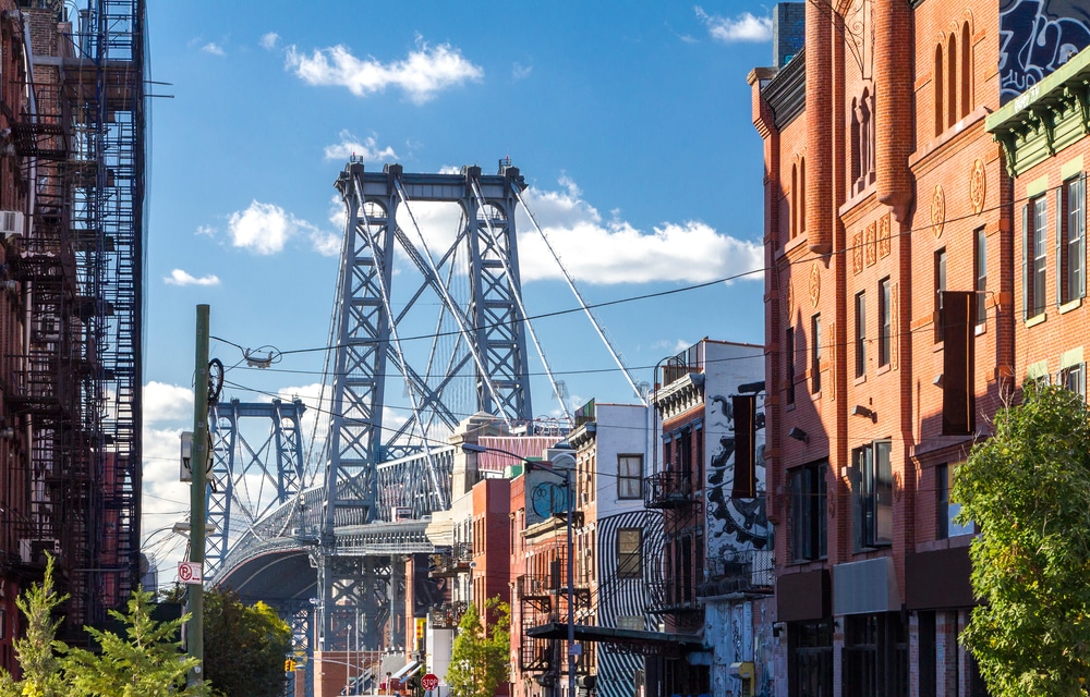 View of the Williamsburg Bridge from a vibrant Brooklyn street, showcasing the unique character of New York City's boroughs. Each borough—Manhattan, Brooklyn, Queens, The Bronx, and Staten Island—offers distinct architecture, culture, and landmarks that contribute to the city’s diverse identity.