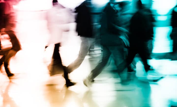 Dynamic and blurry image of people walking under colorful lights, evoking the atmosphere of ghost tours in Lower Manhattan