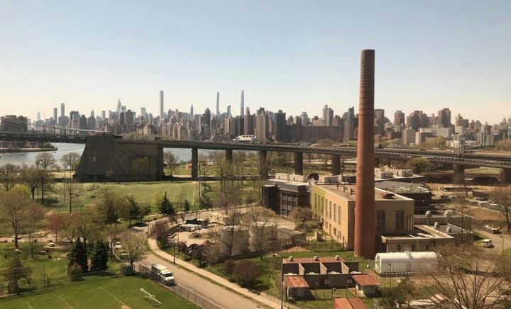 A view from Astoria, Queens, showcasing the sprawling greenery and urban architecture with the New York City skyline in the distance.