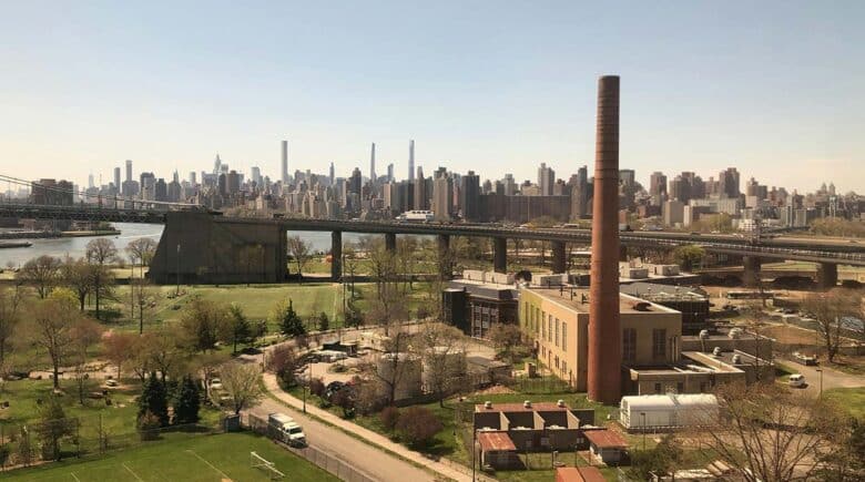 A view from Astoria, Queens, showcasing the sprawling greenery and urban architecture with the New York City skyline in the distance.