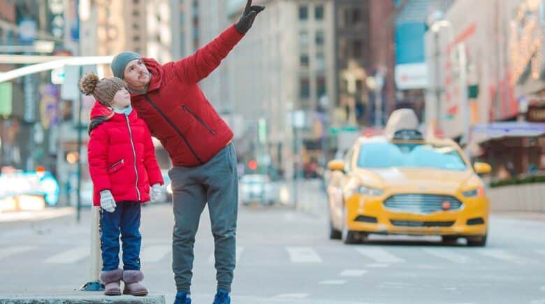 a father and kid enjoying sightseeing in New york with yellow taxi in the background