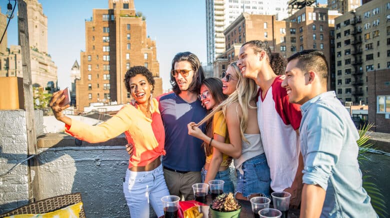 A group of friends enjoying drinks at a rooftop bar with NYC buildings in the background, capturing one of the best Top 10 NYC Activities to experience and a must-do for your NYC Bucket List when exploring Things to Do in New York City.