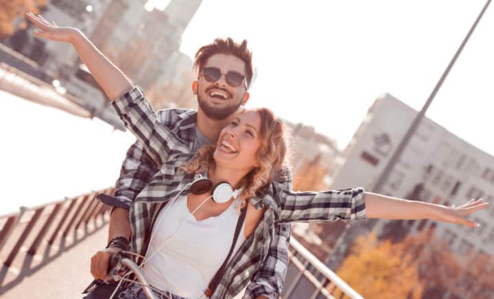 happy young couple riding bicycle in the city