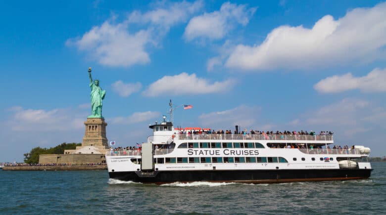 A Statue Cruises Tour Boat in front of the Statue of Liberty