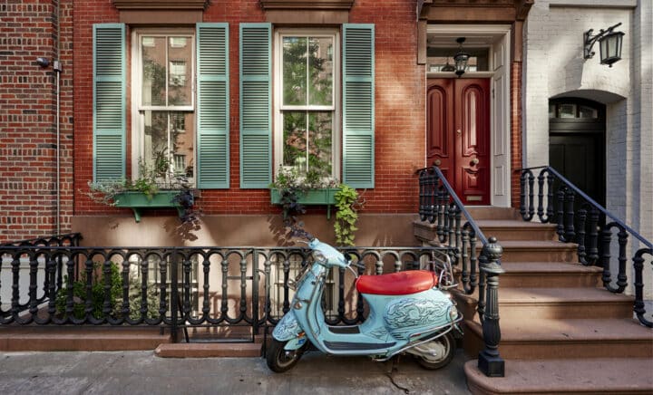 A brownstone building with a vintage scooter in Manhattan