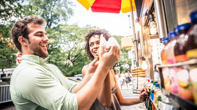 NYC couple enjoying hot dogs from a kiosk