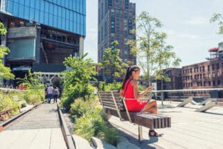New York City lifestyle woman on mobile phone on urban high line park NYC