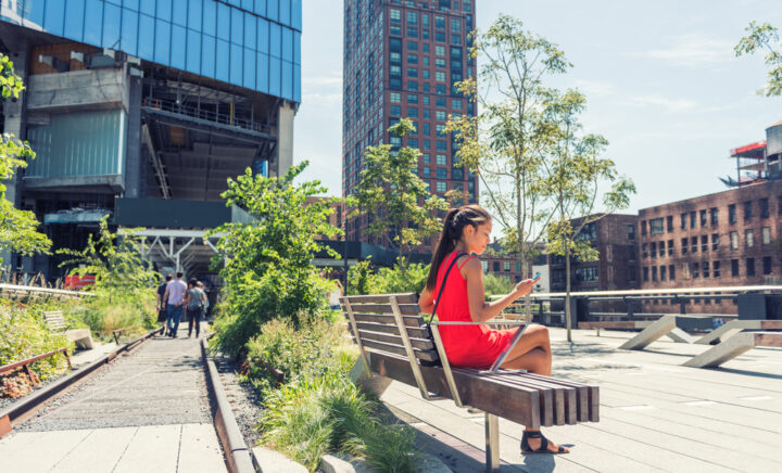 New York City lifestyle woman on mobile phone on urban high line park NYC