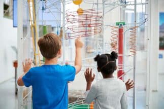 Two kids looking at a science exhibit in a New York City Museum, back view