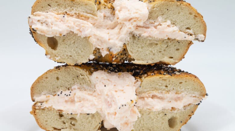 New York City Everything Bagel Cut in Half and Filled with Lox Spread Cream Cheese on a White Plate