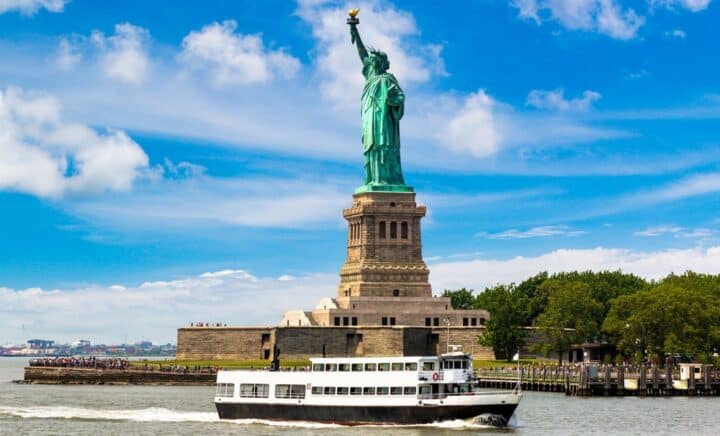 Statue of Liberty and tourist ship ferry in New York City, NY