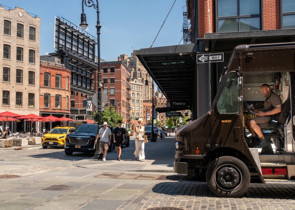 A busy street in the Meatpacking District, New York, with pedestrians, parked cars, a delivery truck
