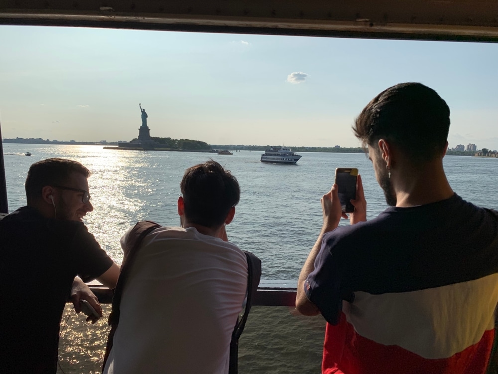 Three men look out over New York's Statue of Liberty as they cruise past on a ferry