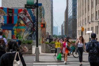 Women crossing Church Street in Manhattan in front of colorful street art mural and buildings