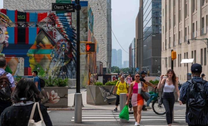 Women crossing Church Street in Manhattan in front of colorful street art mural and buildings