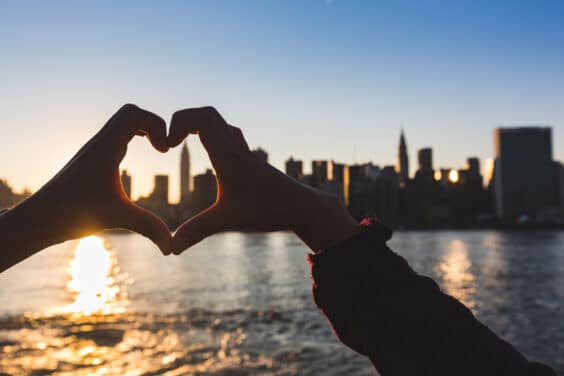 Heart Shaped Hands at Sunset, New York Skyline on Background