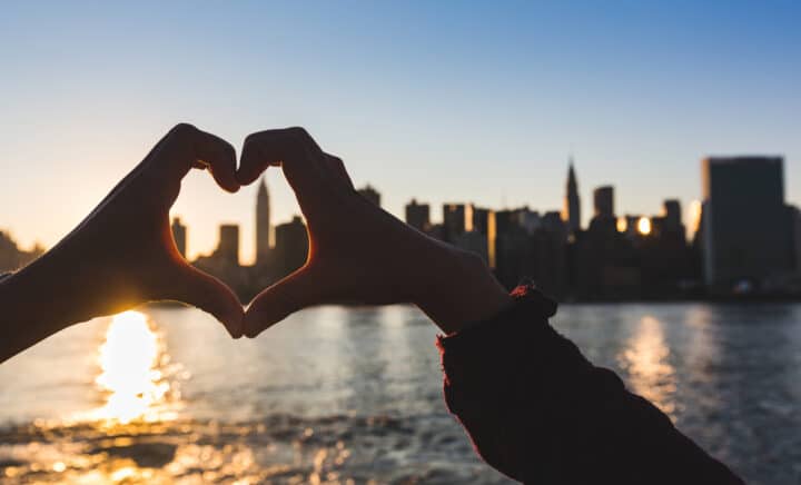 Heart Shaped Hands at Sunset, New York Skyline on Background