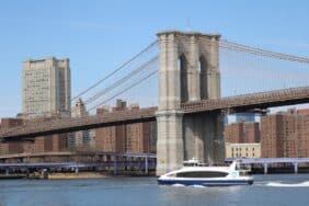 NYC Ferry travels on the East River, Behind is the Manhattan Bridge and the skyscrapers of Lower Manhattan