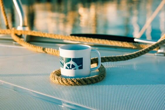 White cup with drawn helm on deck of a white yacht