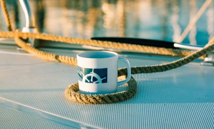 White cup with drawn helm on deck of a white yacht