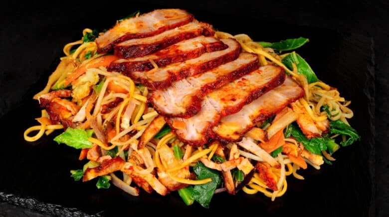 Chinese char siu pork chow mein meal with stir fried noodles and vegetables