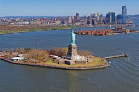 Aerial view of the Statue of Liberty in New York City, USA with Downtown Brooklyn and Governors island in the background