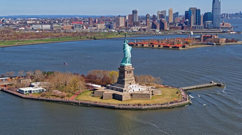 Aerial view of the Statue of Liberty in New York City, USA with Downtown Brooklyn and Governors island in the background