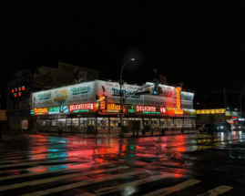 A food street at night, illuminated by colorful lights