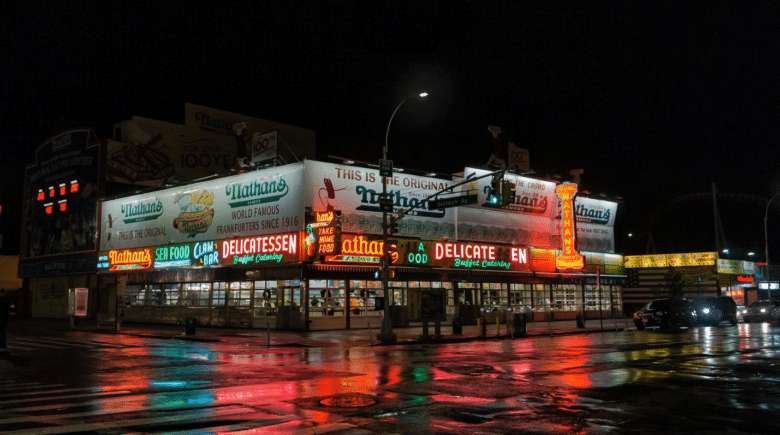 A food street at night, illuminated by colorful lights