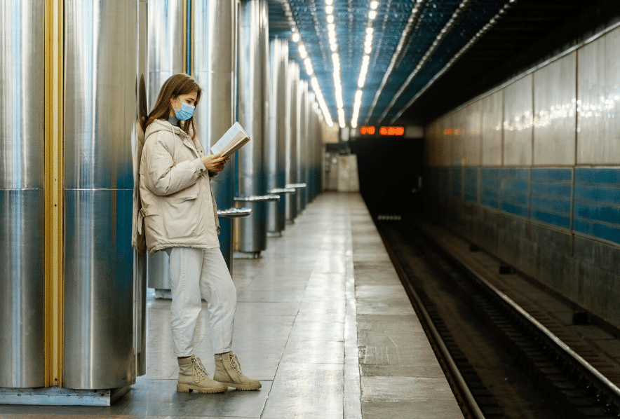 a young woman reading a book in a subway station